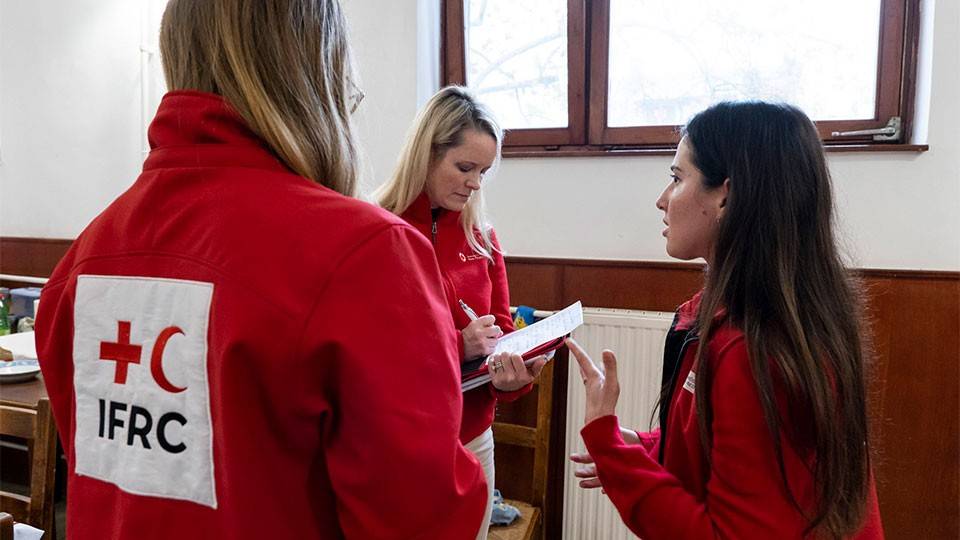 3 Red Cross volunteers talking with each other.