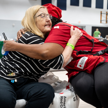 Red Cross volunteer hugging client in a shelter 