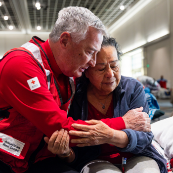 Red Cross volunteer hugging client in a shelter 