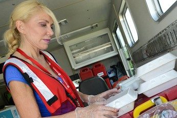 Red Cross volunteer packaging food styrofoam containers.