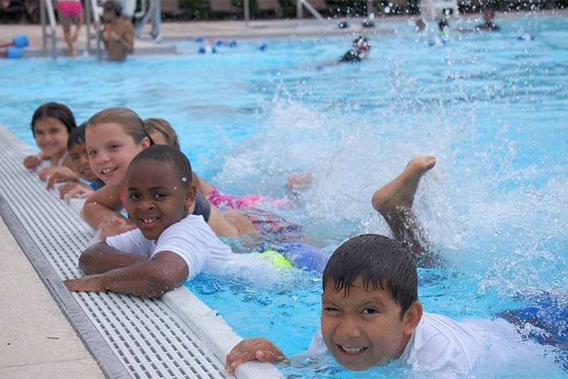 Kids in pool holding onto side kicking their legs