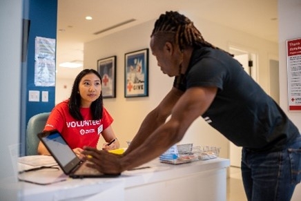 photo of female volunteer sitting at desk talking to male on computer