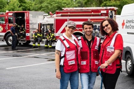 three red cross volunteers in red vest smiling