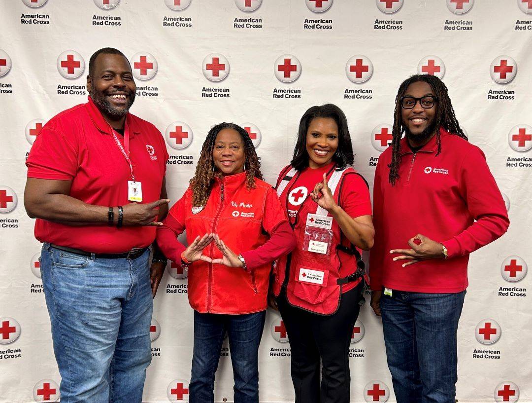 Group of Red Cross volunteers hold up fraternity and sorority hand signs