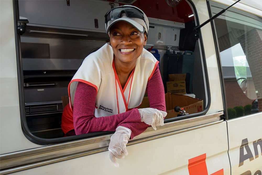 Red Cross volunteer looking out of Red Cross van side window.