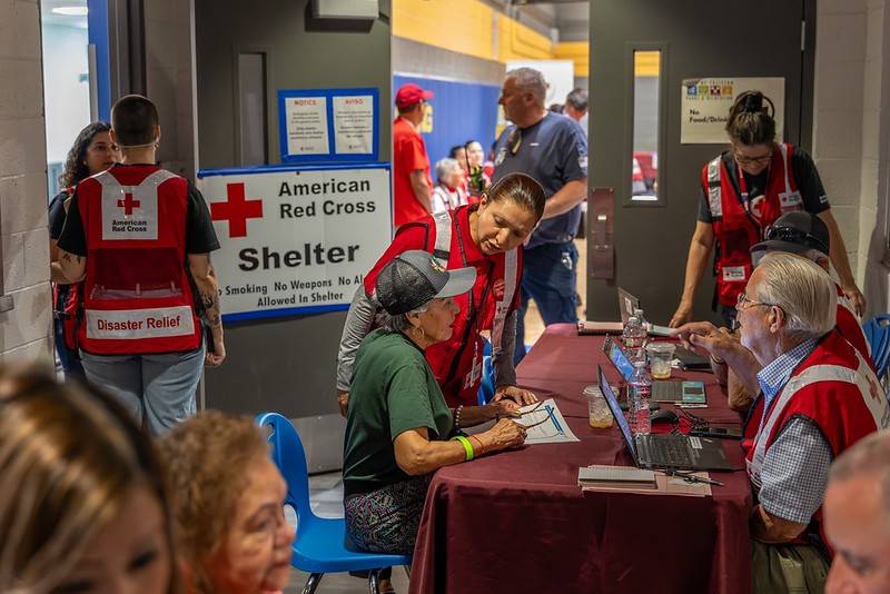 A group of Red Cross volunteers gathering near a desk in a Red Cross shelther.