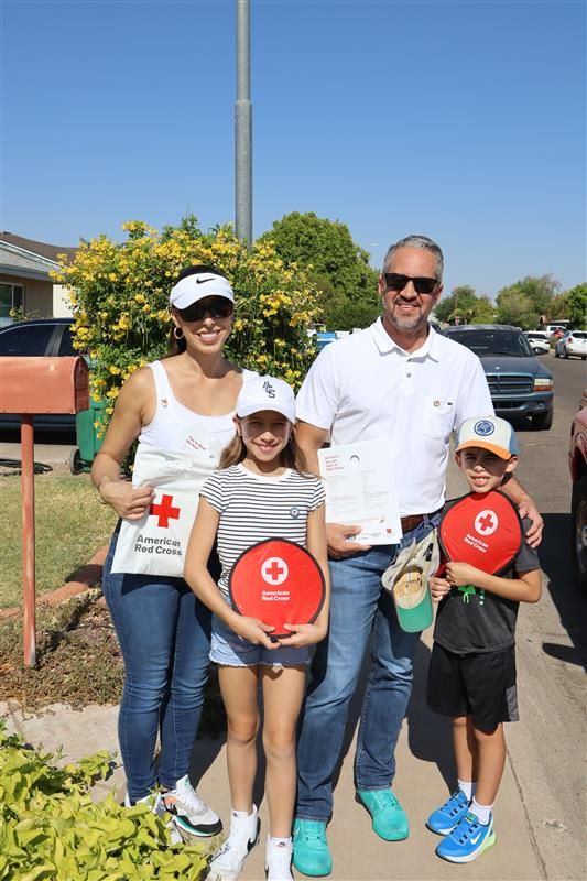 Family of four holding Red Ctross signs.