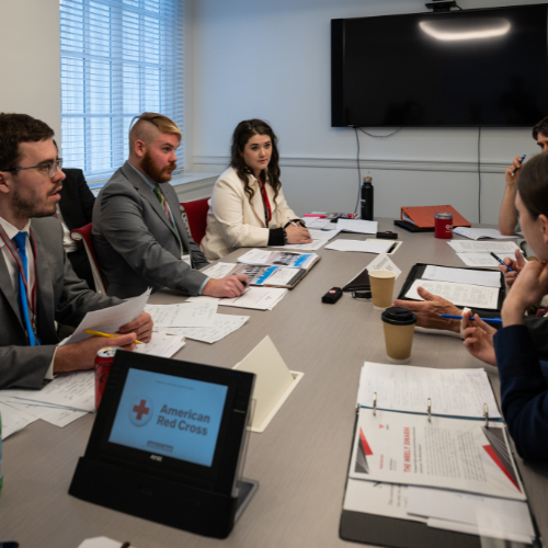 A group of people in suits sitting at a table with papers in front of them.