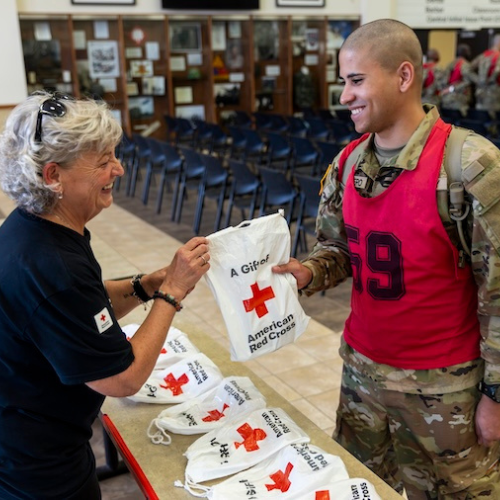A service member recieving a Red Cross goodie bag from a volunteer.