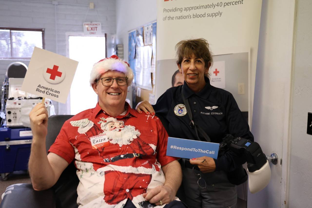 Husband and wife hold signs at Red Cross blood drive