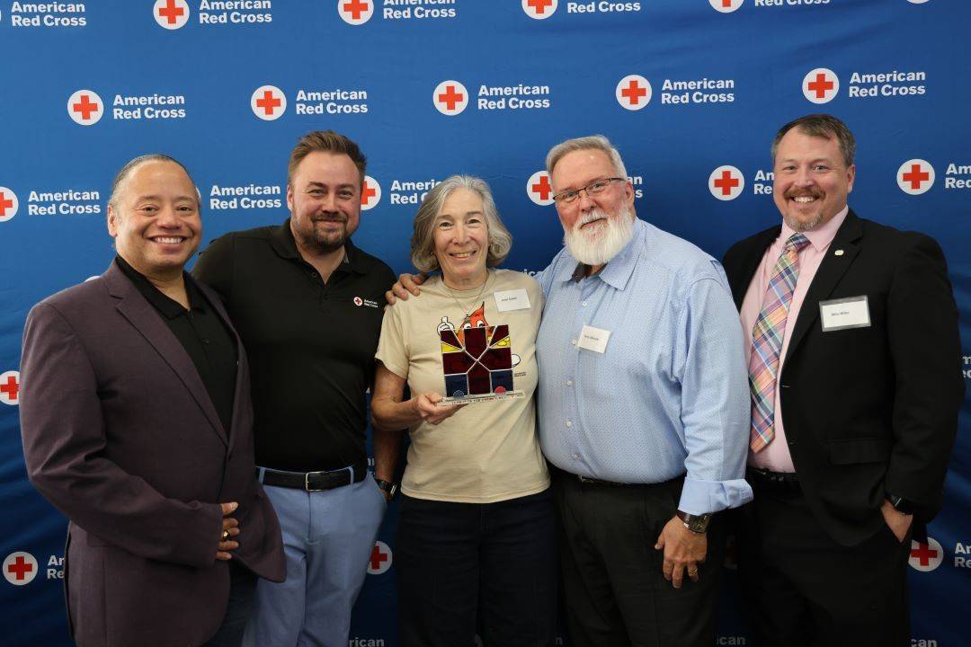 Group of people stand in front of Red Cross back drop