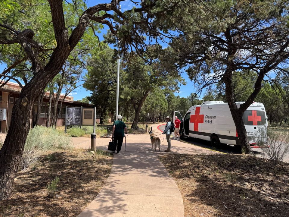 Two red cross volunteers carrying suplies to a home