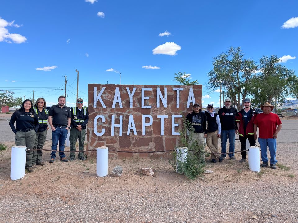 Group of Red Cross volunteers standing in front of "Kayenta" sign