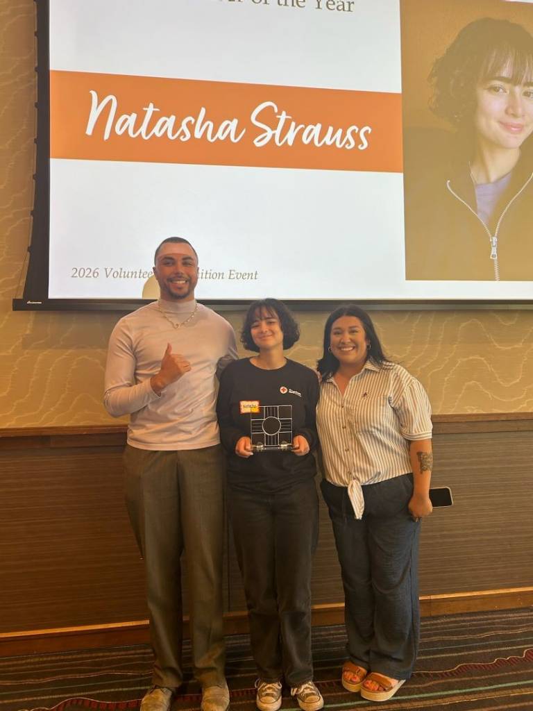 Natasha holds Red Cross award while standing between two other people