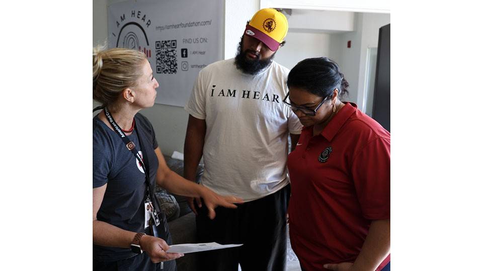 Red Cross volunteer, Paige Singer, discusses with Joey and his mother Legalo the best places to install smoke detectors in Joey’s apartment.