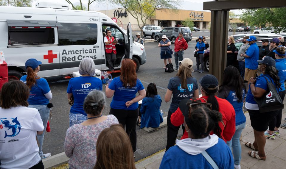 Red Cross volunteer in Emergency vehicle talking to a arge group of people