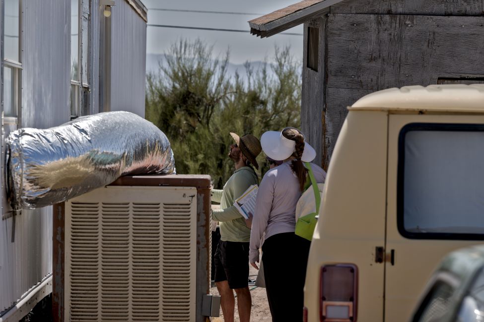 Two Red Cross volunteers in hats surveying home