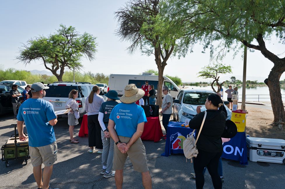 A group of volunteers huddled around a van and a table