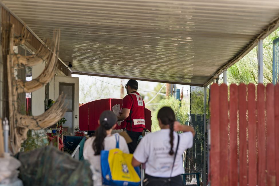 Three Red Cross volunteers on the porch of a home.