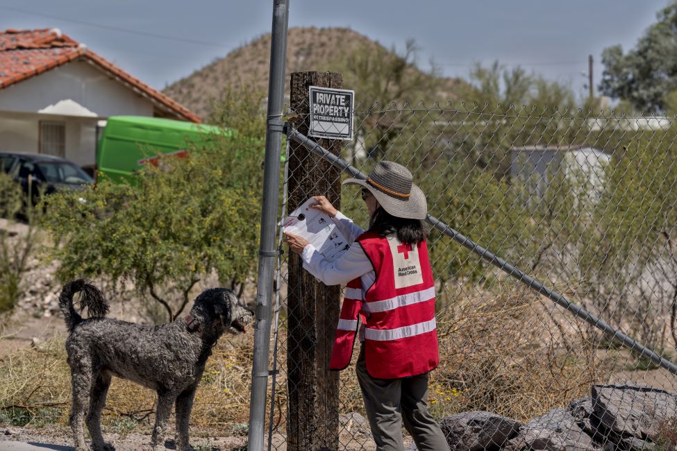 A Red Cross volunteer posting a flyer on a fence.