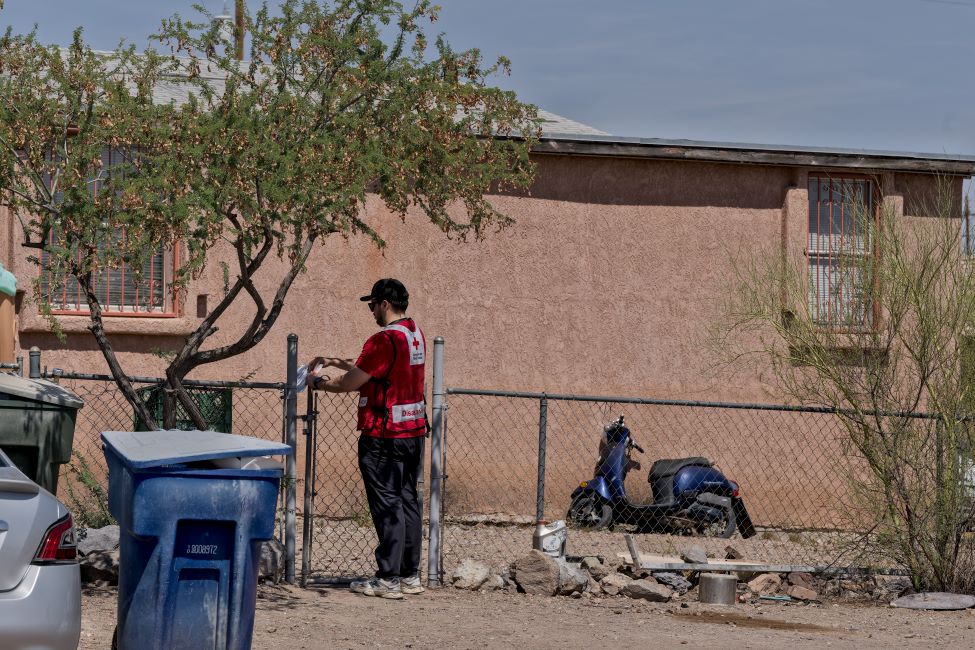 A Red Cross volunteer posting a flyer on a fence.