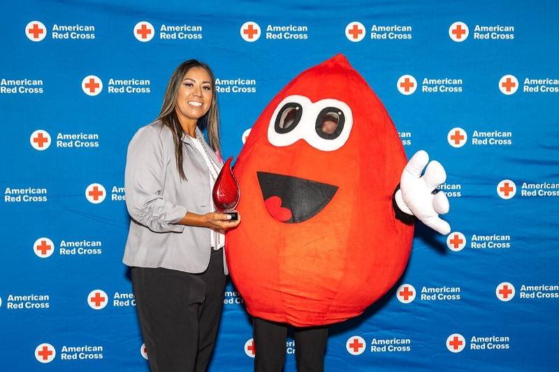 Woman poses with award next to Buddy the blood drop