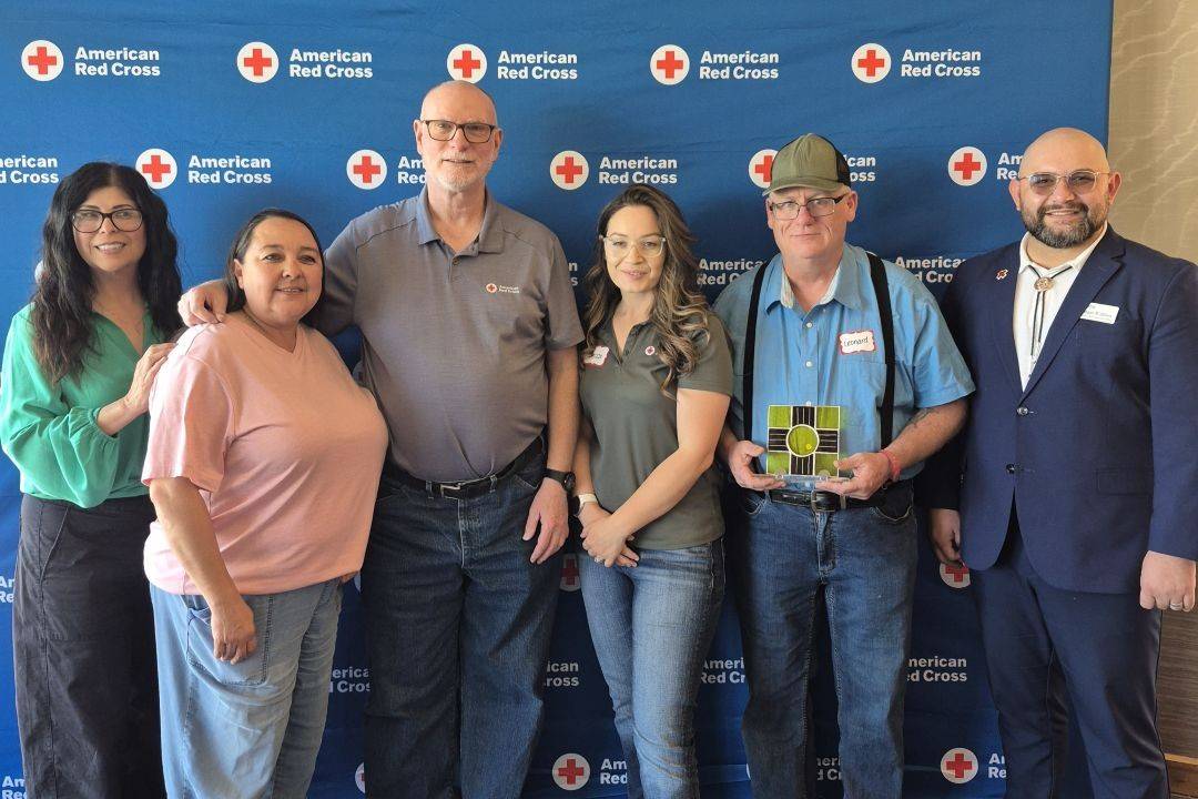 Group of people stand in front of Red Cross back drop