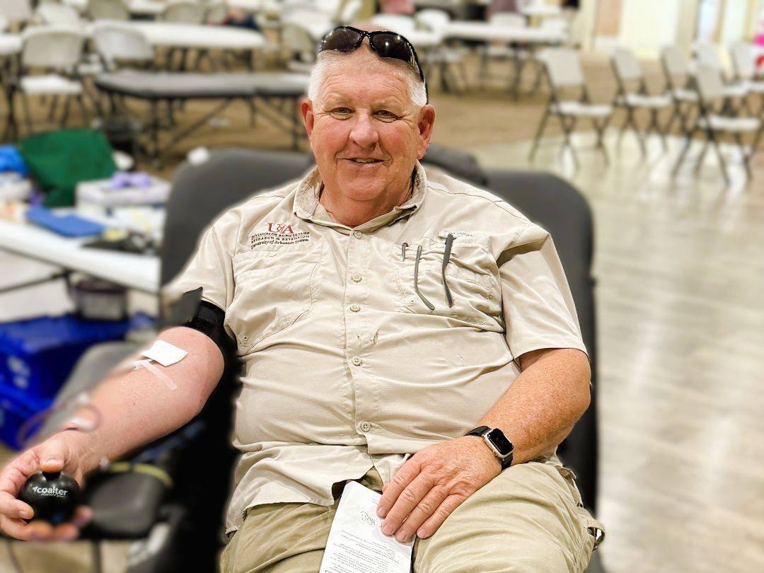 Man sits in blood donation chair donating blood