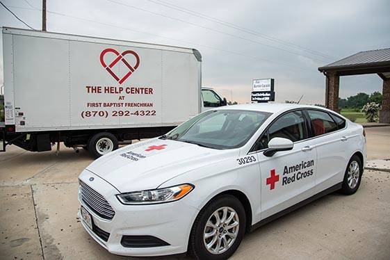 Red cross car parked in front of truck with The Help Center logo