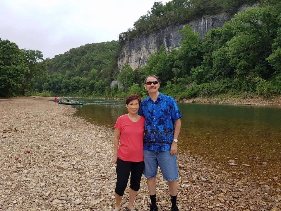 Man and woman stand in front of river and mountains
