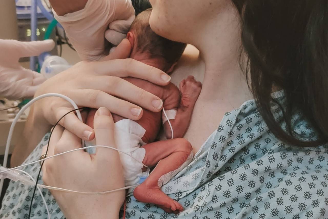 Mother holds newborn baby in NICU