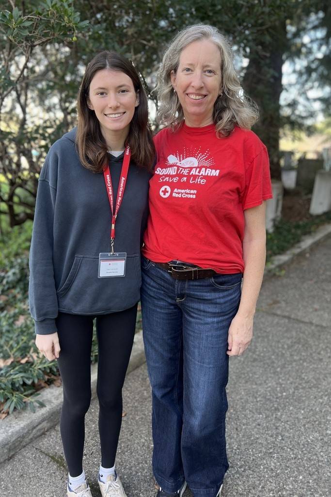 Two women stand together wearing Red Cross shirts