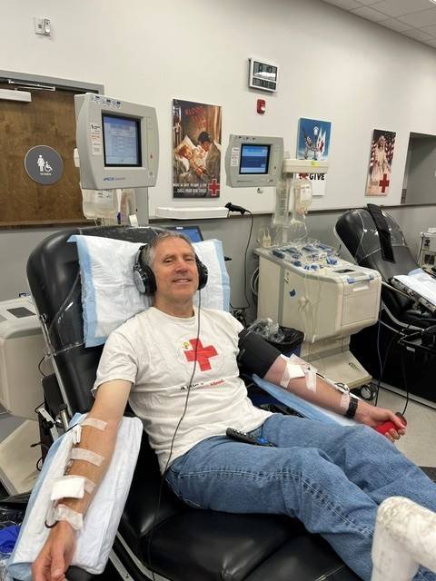 Michael donates platelets while wearing Red Cross shirt