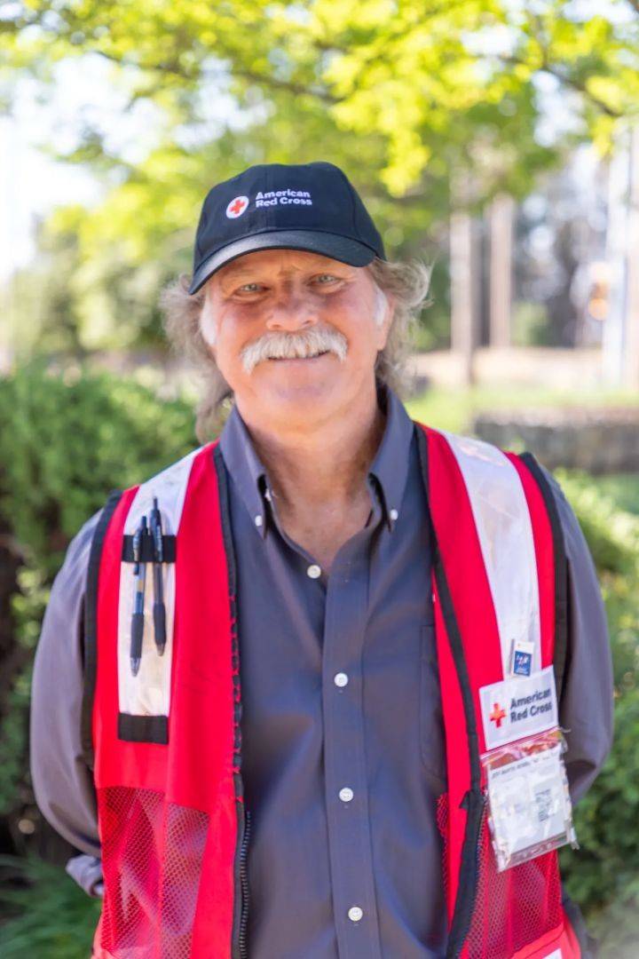 Headshot of man in Red Cross hat and vest standing outside