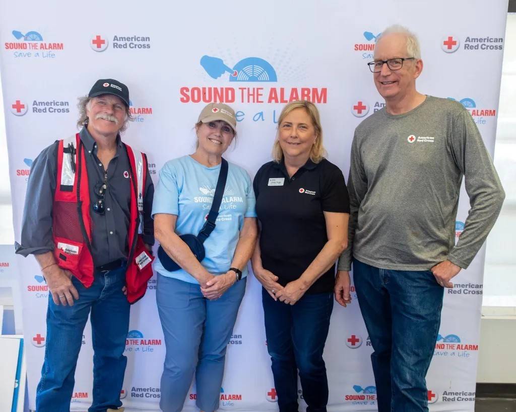 Four people stand in front of Sound the Alarm banner