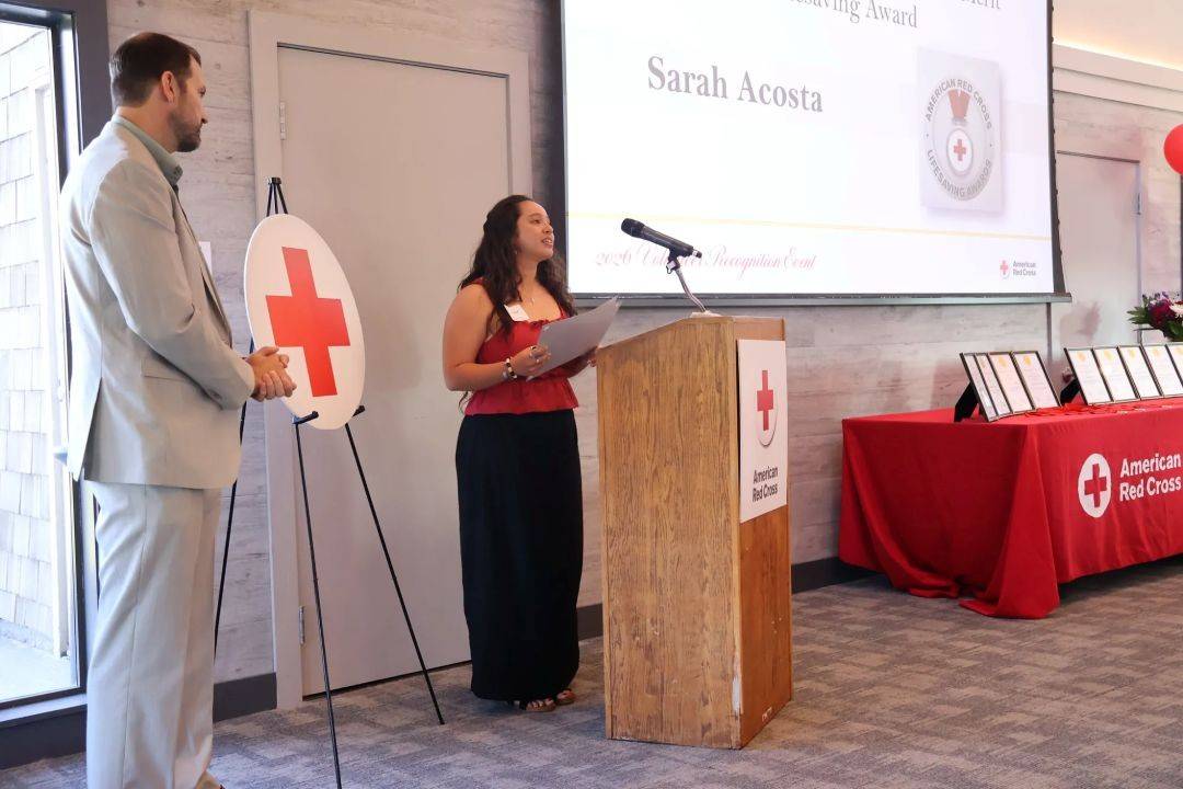 Woman stands behind podium at Red Cross lifesaving event