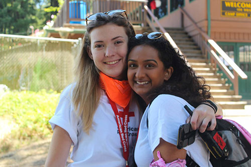 two young women embrace each other and smile for picture.