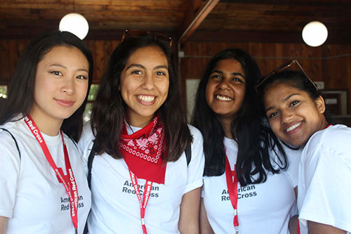 four ldc students wearing red cross shirts smile for picture.