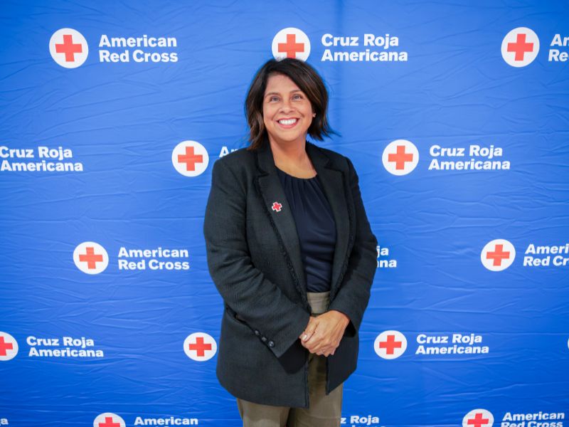 woman standing in front of red cross backdrop