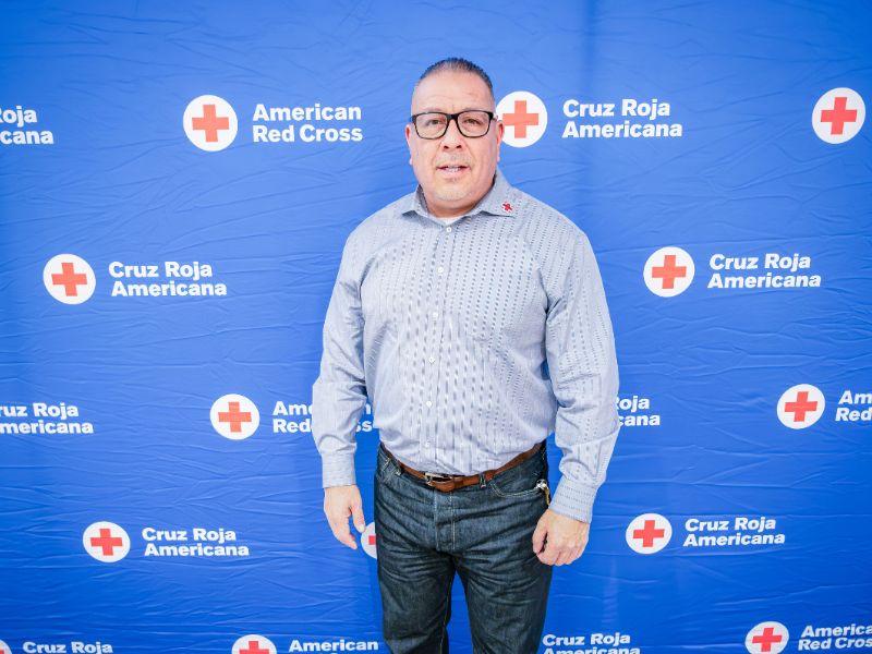man standing in front of red cross backdrop