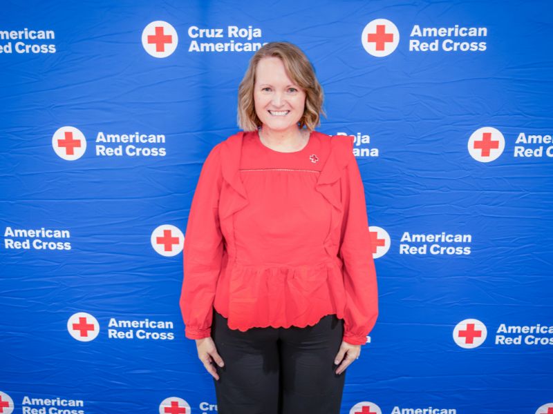 woman standing in front of red cross backdrop