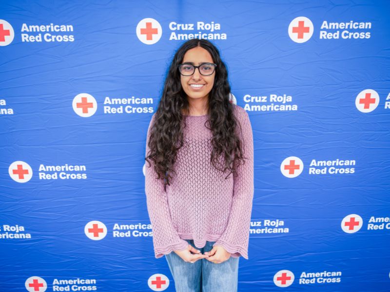 young woman standing in front of red cross backdrop