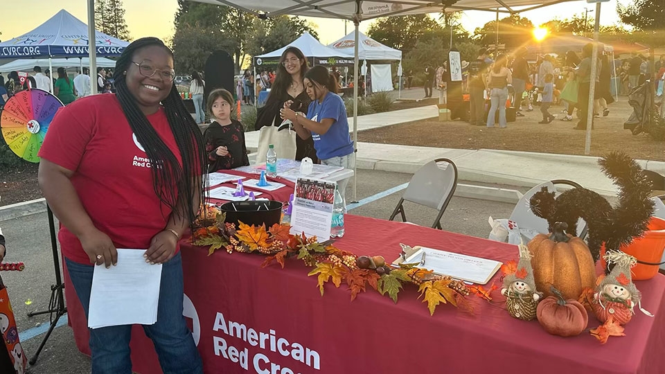 red crosser Tyniquea Edwards working at a Red Cross booth at a fair.