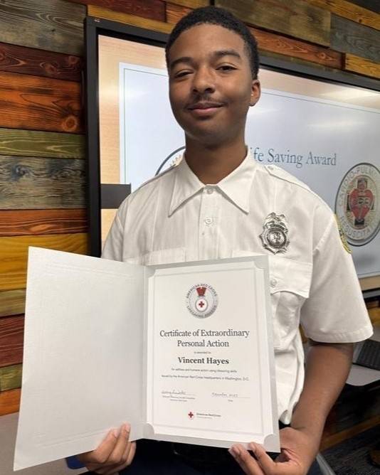 Young man holds lifesaving award