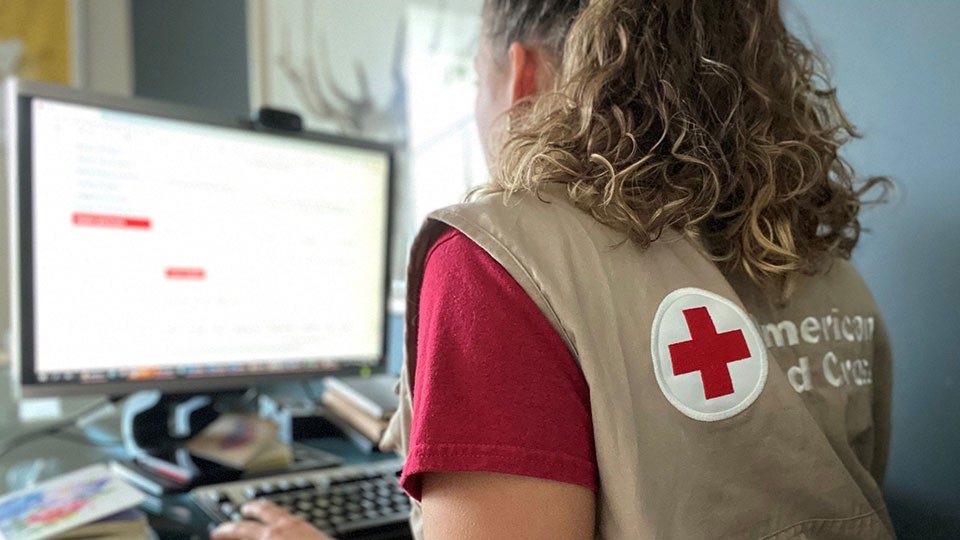 A Red Cross volunteer typing on the computer keyboard.