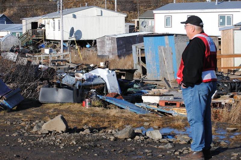 Man overlooks damaged homes while wearing Red Cross vest