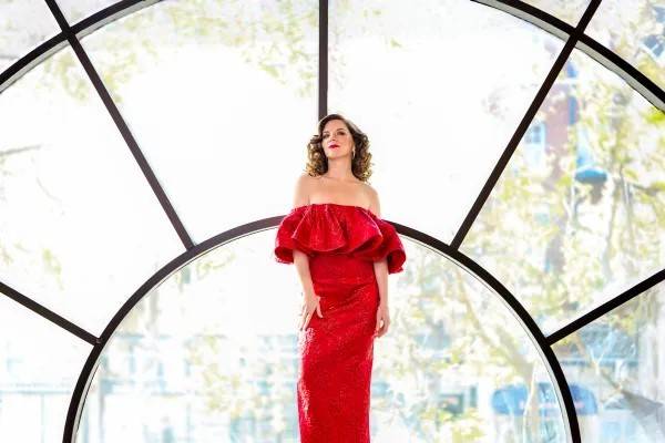 Woman in red dress stands in front of stained glass windows