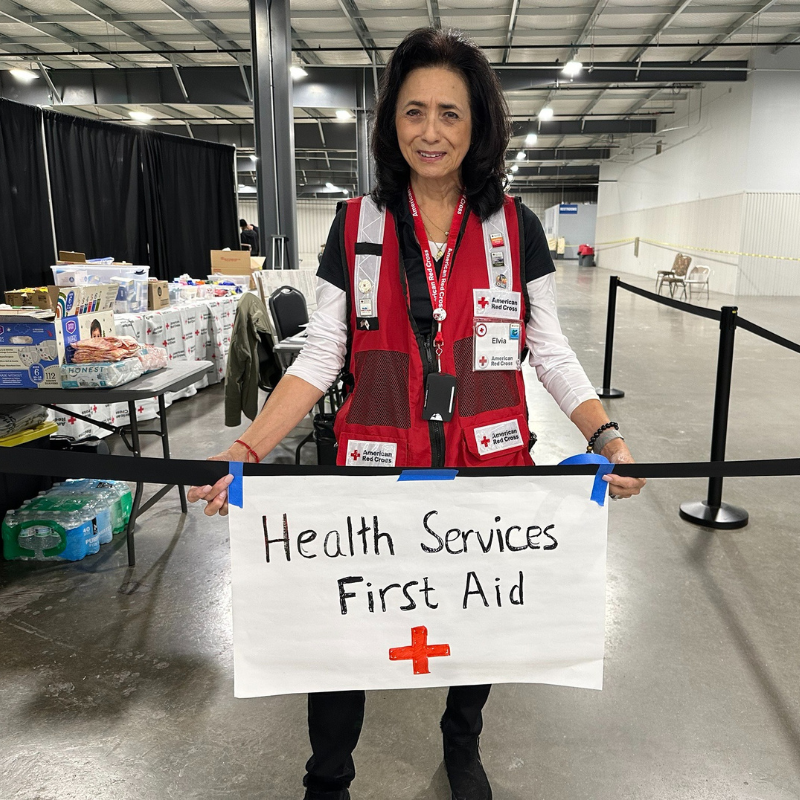 Elvia holding "Health Services First Aid" sign.