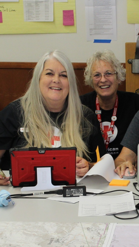Julie at a tabling smiling with other volunteers.