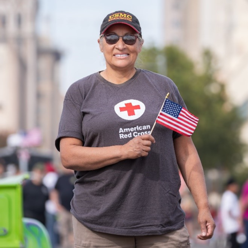 Susan holding an american flag wearing a red cross tshirt.